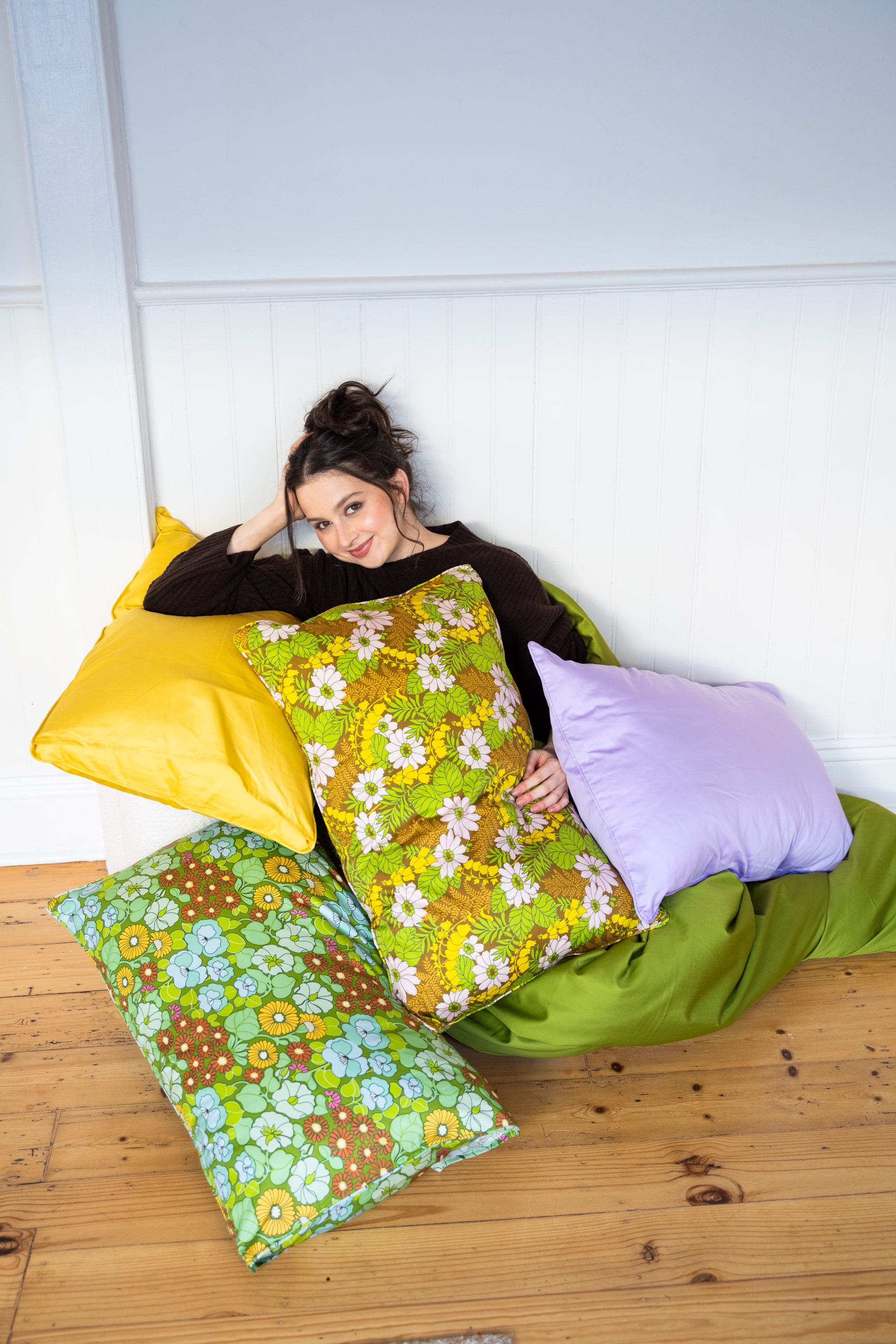 A woman relaxing among colourful limited-edition Pillowcase Parlour prints
