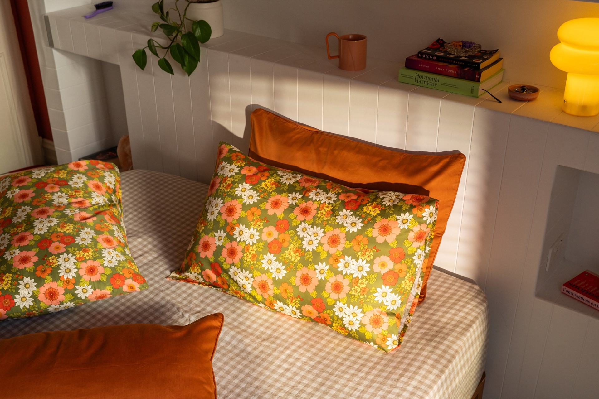 Mamma floral pillowcases styled on a sunlit bed with rust cushions