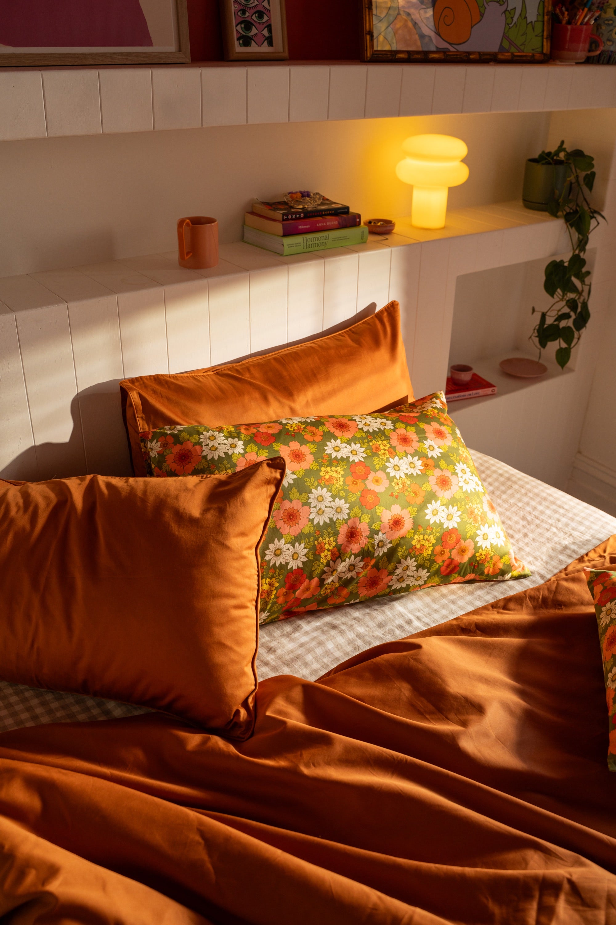 Mamma floral pillowcases layered with rust bedding in warm afternoon light