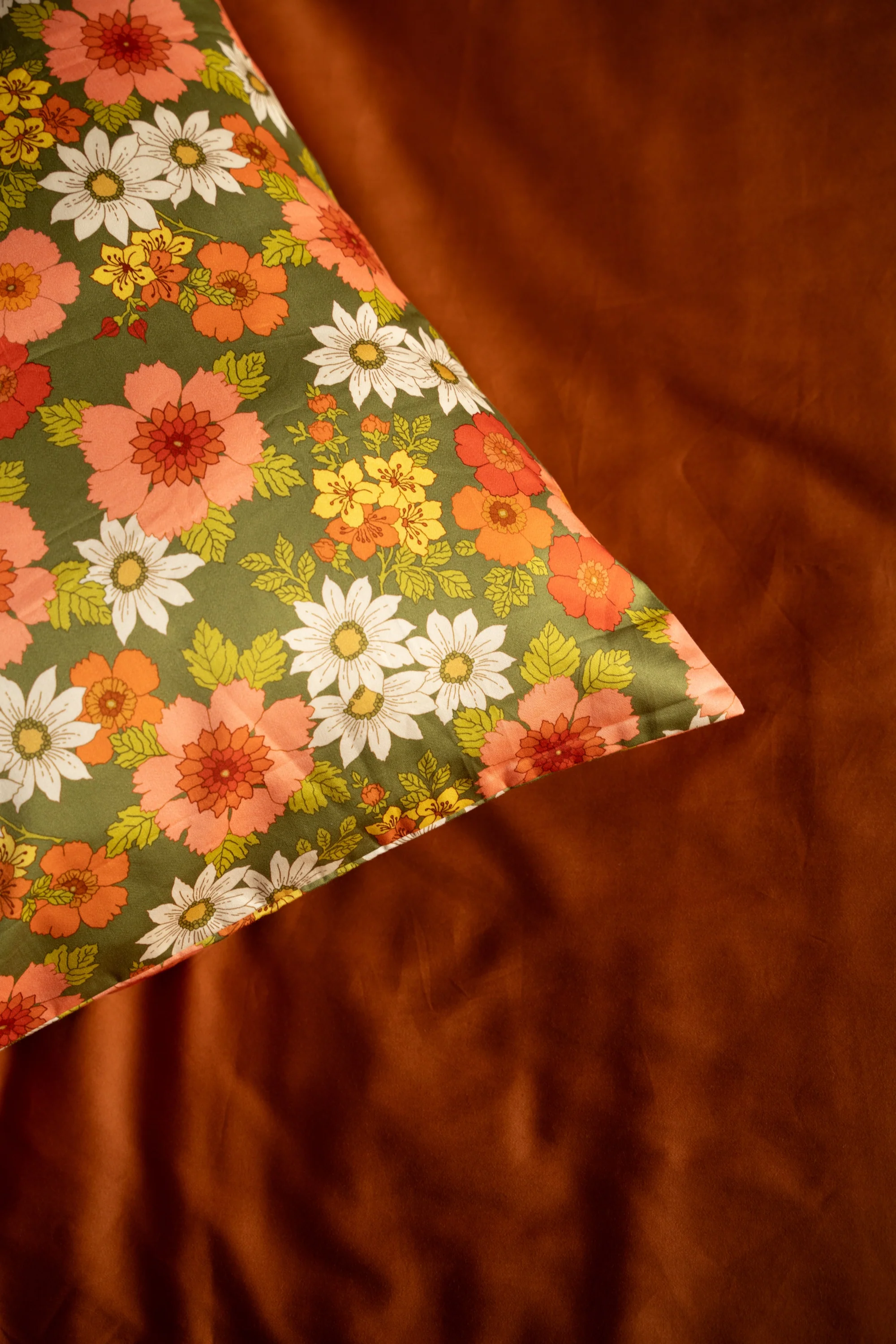 Close-up of the Mamma floral cotton print against rust bedding