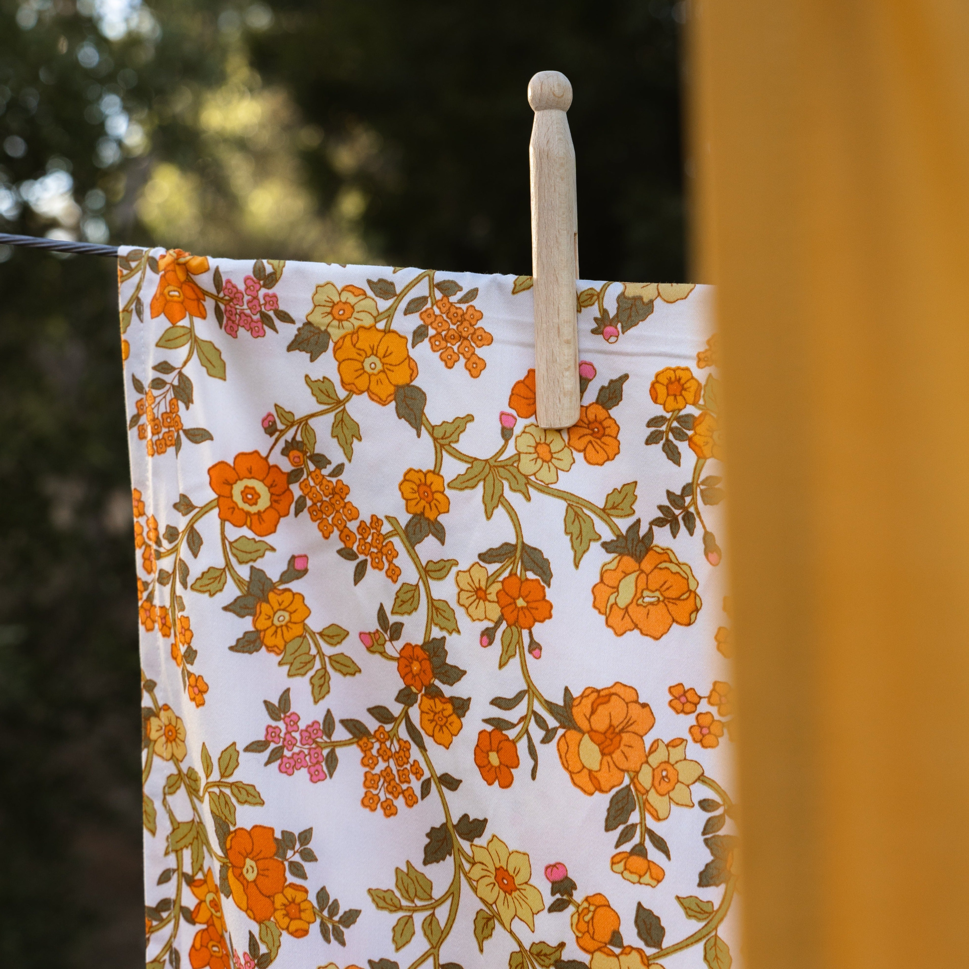 Gorgeous and delicate vintage floral cotton sheet hanging on  a Hills Hoist with a wooden dolly peg.a